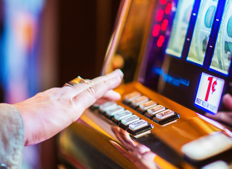 Une personne âgée joue à une machine à un sous dans un casino