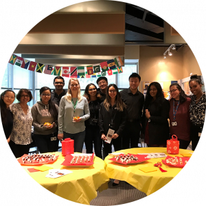 OLG employees standing behind two yellow round tables with snacks in celebration of diversity.