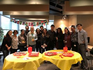 OLG employees standing behind two yellow round tables with snacks in celebration of diversity.
