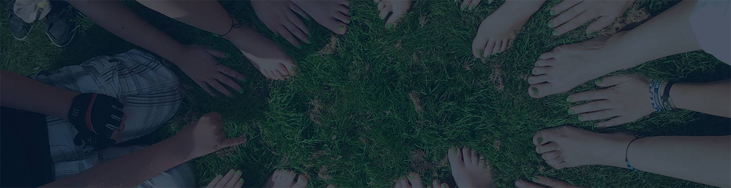 Hands and feet gathered in a circle on green grass.