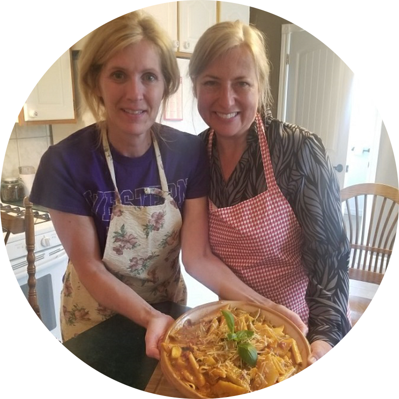 Two OLG employees wearing aprons and holding a home cooked dish.