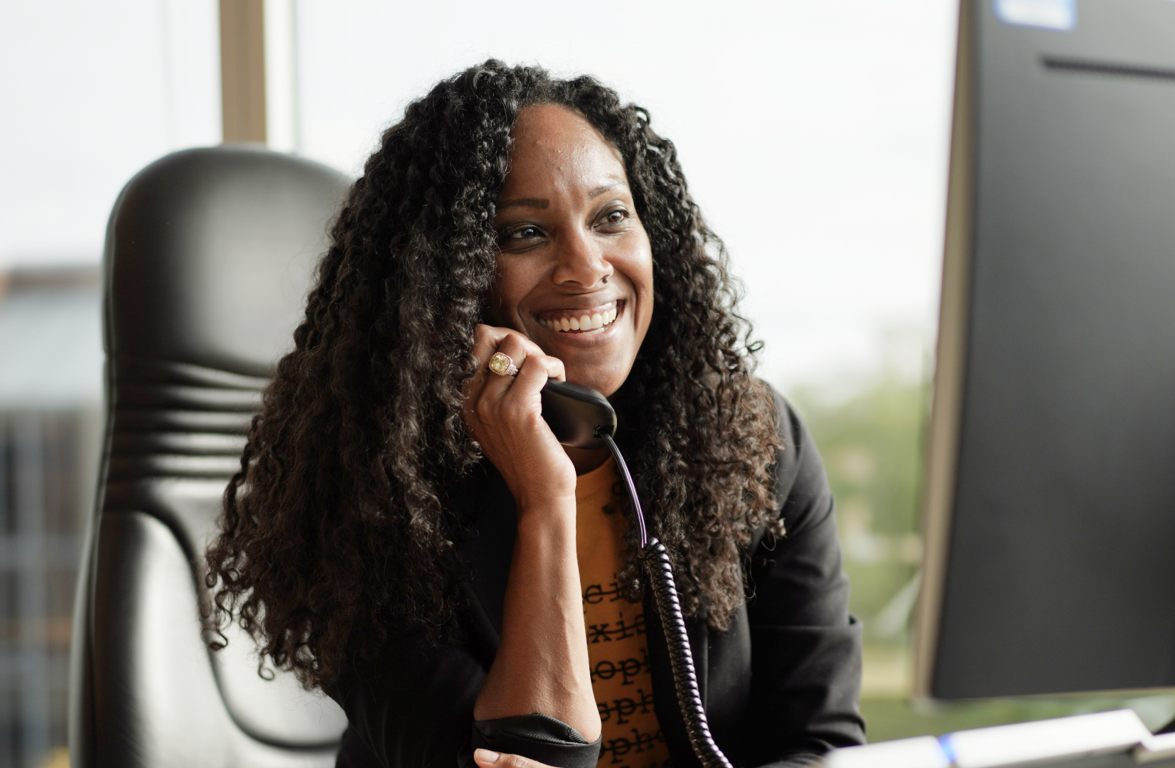 Seated OLG employee talking on phone while smiling