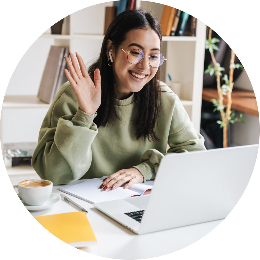 View of a person smiling and waving while looking at a laptop.