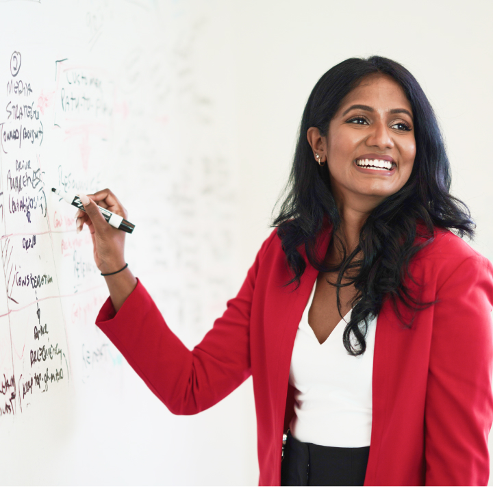 OLG employee writing on whiteboard while smiling