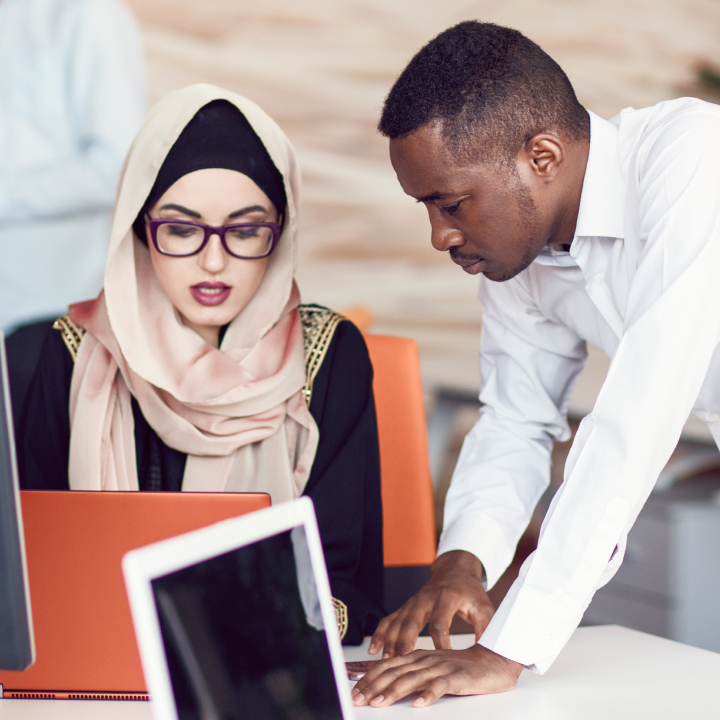 A person helping another person on a work laptop