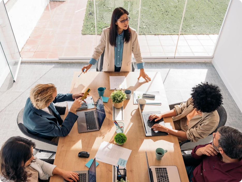 View of people sitting down at a desk with their laptops in front of them.