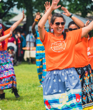 View of people wearing orange-coloured shirts with their hands in the air.